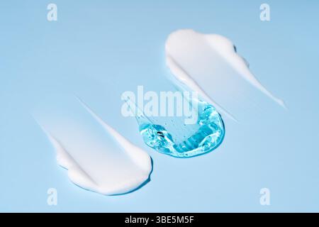 Ein blaues Gel neben weißer Creme ist künstlerisch auf einer hellen Oberfläche verteilt und zeigt glatte Texturen und lebendige Farben. Licht leuchtet durch den Stockfoto