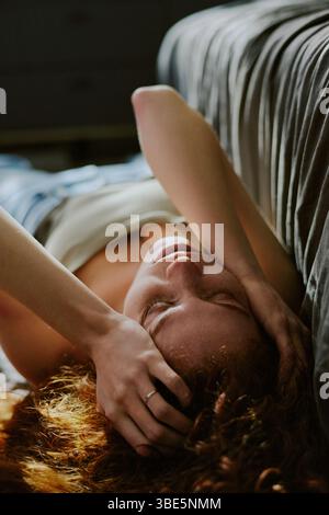Frau, die mit der Hand auf dem Bodenbelag liegt, sie leidet unter tiefen Depressionen Stockfoto