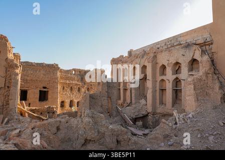 Verwitterte und zerbröckelnde Gebäude in Al Hamra, einem verlassenen Lehmbad, vor einem klaren blauen Himmel in Oman. Dieses Bild erfasst den Zerfall und die Historie Stockfoto