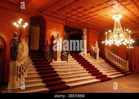 Die große Marmortreppe des Theatro da Paz in Belém, Pará, beleuchtet von einem verzierten zentralen Kronleuchter und flankiert von bronzenen Fackelstatuen. Stockfoto