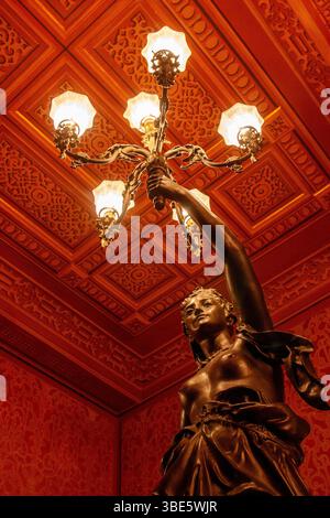 Bronzestatue am Eingang des Theatro da Paz mit komplizierten Kassettendecken und Beleuchtungselementen im Foyer der Belle Epoque. Stockfoto