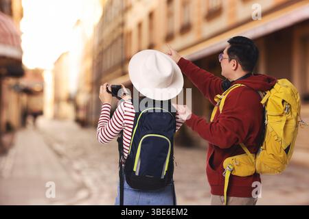 Touristen mit Rucksäcken, die Fotos auf der Stadtstraße machen, Rückansicht Stockfoto