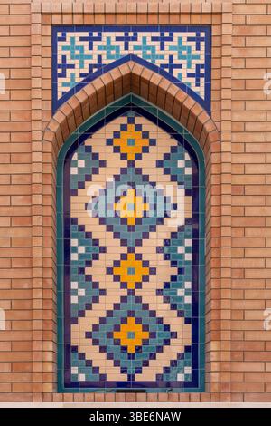 Geometrische Rautenmuster in blauen und goldenen Fliesen bilden atemberaubende dekorative Tafel an der traditionellen islamischen Gebäudewand in A'ali. Stockfoto