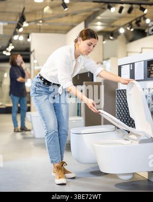 Weibliche Kundin, die sich weiße Toiletten im Verkauf in einem modernen Geschäft oder Einkaufszentrum ansieht Stockfoto