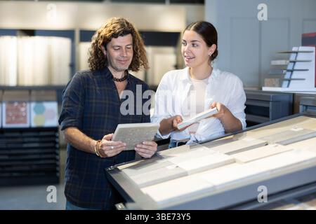 Ehemann und Ehefrau wählen Keramikfliesen für die Inneneinrichtung im Baumarkt Stockfoto