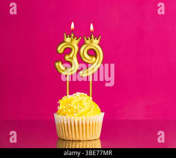 Geburtstagsfeier mit der Kerze Nummer 39 - Gelber Cupcake auf rosa Hintergrund Stockfoto