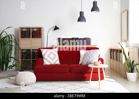 Rotes Sofa und Bücherregale mit vielen Büchern im Wohnzimmer Stockfoto