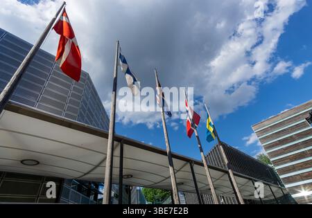 Nordische Fahnen hängen an einem ruhigen Tag vor den Nordischen Botschaften in Berlin, ohne dass der Wind sie aufhebt, was eine ruhige und reflektierende Szene schafft. Stockfoto