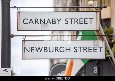 Straßenschilder für Carnaby Street und Newburgh Street im lebhaften Einkaufsviertel Londons. Die Schilder sind ikonisch im Mode- und Kulturzentrum der Stadt. Stockfoto