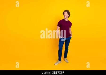 Porträt eines fröhlichen jungen Mannes in lässiger Mode, der vor einem leuchtend gelben Hintergrund mit modernem Stil posiert Stockfoto