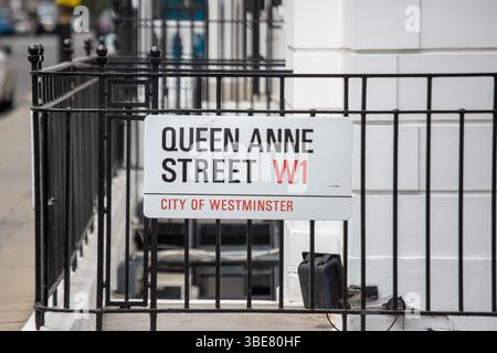 Straßenschild zur Queen Anne Street in Westminster, London. Das Schild ist an einem Metallzaun auf einem Bürgersteig der Stadt angebracht. Stockfoto