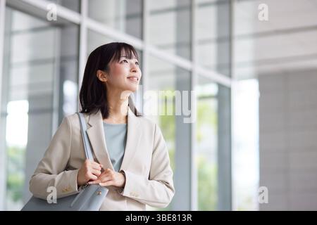 Japanische Geschäftsfrau geht aus dem Büro Stockfoto