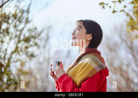 Japanerin genießt die Natur mit einer Tasse Kaffee in den Winterbergen. Stockfoto