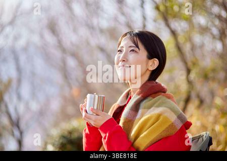 Japanerin genießt im Winter die Natur mit einer Tasse Kaffee in den Bergen Stockfoto