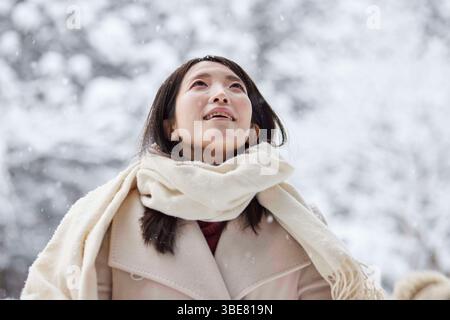 Japanerin, die einen Schal trägt, steht im Winter in einem verschneiten Land. Stockfoto