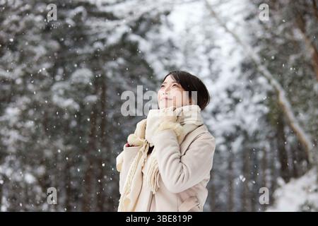 Japanerin, die einen Schal trägt, steht im Winter in einem verschneiten Land Stockfoto