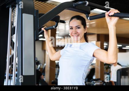 Junge, schöne asiatische Frau mit sportlichem Aufbau und guter Figur, die Pull-ups macht Stockfoto