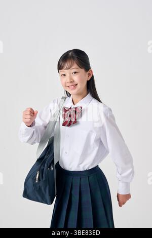 Japanisches Mädchen der Junior High School mit Schultasche auf weißem Hintergrund Stockfoto