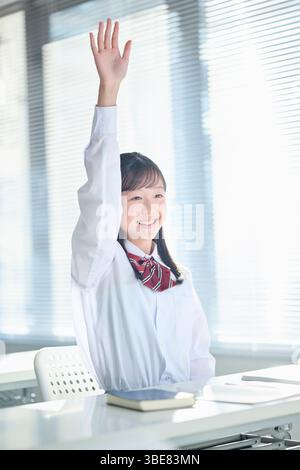 Mädchen der Junior High School heben sich die Hände in der Klasse Stockfoto