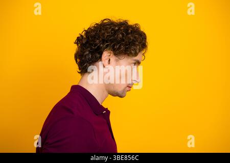 Seitenprofil eines stilvollen jungen Mannes auf leuchtendem gelbem Hintergrund, das lässige und trendige Mode zeigt Stockfoto