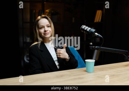 Content Creator, der mit einem Mikrofon einen Audio-Podcast in einem gemütlichen Heimstudio aufnimmt, strahlt Glück und Kreativität aus Stockfoto