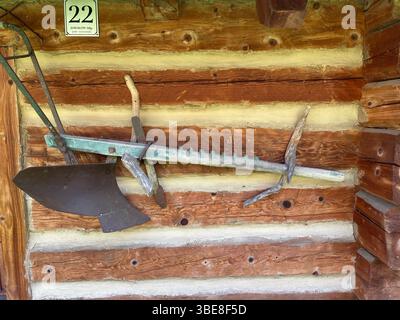 Ein rostiger alter Pflug hängt an einer Holzwand. Der Hobel ist an einem Holzgriff und ein Holzgriff an einem Holzgriff befestigt Stockfoto