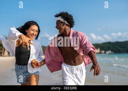 Interrassisches Paar, das einen romantischen Strandurlaub genießt und Liebe, Lachen und Zweisamkeit genießt Stockfoto