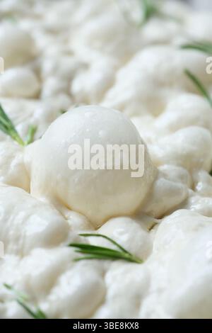 Flauschiger Brotteig, der in einer mit Pergamentpapier ausgelegten, rechteckigen Pfanne aufsteigt. Stockfoto