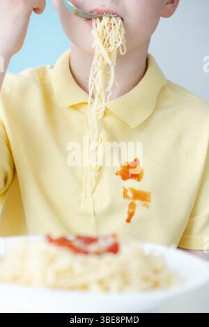 Schmutzige Tropfen Tomatensauce oder Ketchup Flecken auf gelber Kleidung während des Mittagessens. Stockfoto
