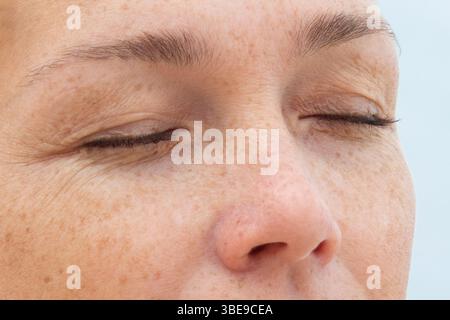 Frauengesicht mit geschlossenen Augen, natürliche Haut und Falten um die Augen Stockfoto