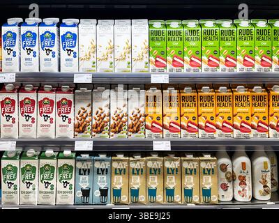 Eine Vielzahl pflanzlicher und laktosefreier Milchprodukte, die in Kühlregalen in einem Lebensmittelgeschäft ausgestellt werden. Stockfoto