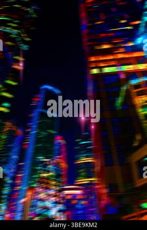 Nächtliche Stadtlichter. Hell leuchtende Lichter eines Großstädtenviertels unter Dämmerungshimmel am Abend auf verschwommenem Hintergrund Stockfoto