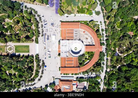Blick aus der Vogelperspektive auf das Zappeion Mansion in Athen, umgeben von symmetrischen Gärten und von Bäumen gesäumten Pfaden, die an einem sonnigen Tag von der Drohne erfasst werden. Stockfoto