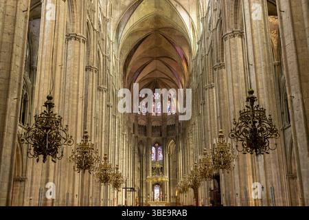 Beeindruckender Blick auf das Kirchenschiff und die Buntglasfenster der Kathedrale von Bourges mit Kronleuchtern, die von der Decke hängen Stockfoto
