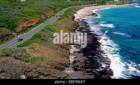 Küstenautobahn mit Wellen, die entlang der felsigen Küste Hawaiias krachen. Stockfoto