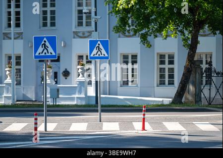Zwei Fußgängerschilder stehen auf einer Straße mit einem historischen Gebäude im Hintergrund. Stockfoto