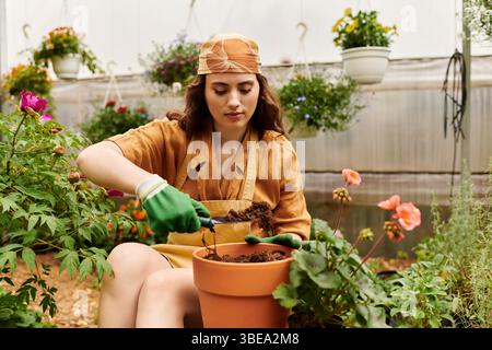 Eine junge Frau im Kopftuch zieht in ihrem Gewächshaus helle Pflanzen an und liebt die Gartenarbeit. Stockfoto