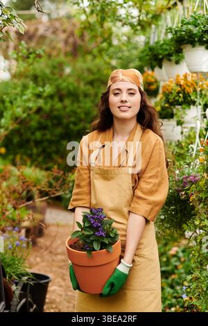 In einem ruhigen Gewächshaus pflegt eine junge Frau ihre lebendigen Pflanzen, während sie ein Kopftuch trägt. Stockfoto