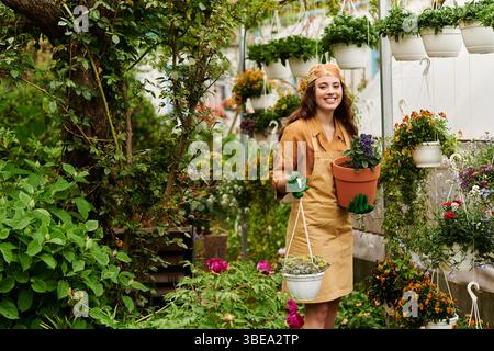Hell und fröhlich pflanzt eine junge Frau in einem blühenden Gewächshaus. Stockfoto
