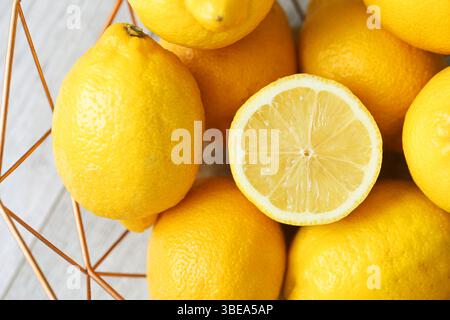 Frische gelbe Zitronen. In Scheiben geschnittene Zitrone in der Mitte. Hintergrund der Zitrusfrüchte. Leuchtende, lebendige Textur. Natürliche Vitamin-C-Quelle. Saftiges und gesundes Essen. Stockfoto