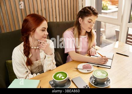 Zwei schöne junge Frauen genießen sich Gesellschaft, während sie Geschichten und Desserts teilen. Stockfoto