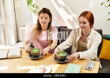In einem trendigen Café verbringen zwei Freunde einen Moment, während sie ihre Matcha-Drinks genießen. Stockfoto