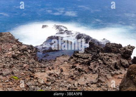 Maui, Hawaii, USA - 9. April 2022: Wellen krachen gegen die felsige Küste und schaffen eine dynamische Szene der Kraft und Schönheit der Natur. Stockfoto