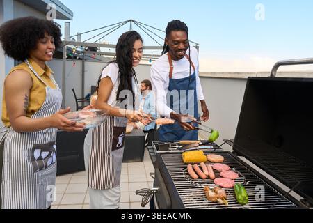 Freunde grillen Essen, genießen eine Grillparty auf dem Dach Stockfoto