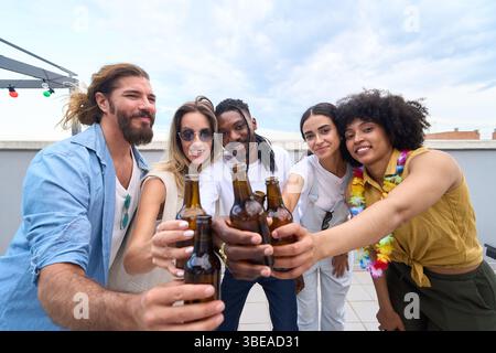 Freunde, die auf der Dachparty mit Bierflaschen tosten Stockfoto