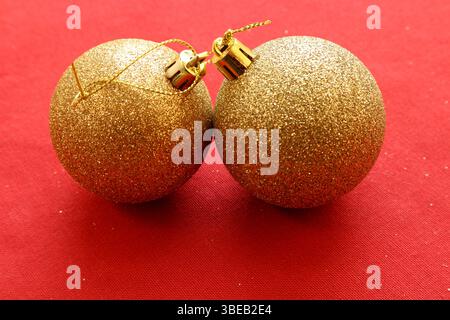 Frohe Weihnachten. Minimalistische Stillleben Deko. Goldene Kugeln mit rotem Hintergrund. Nahaufnahme und isoliert. Kopierbereich zum Hinzufügen von Text. Stockfoto