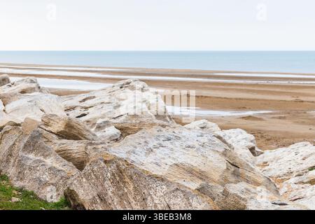 Eine ruhige Strandlandschaft mit großen Felsen, einer sandigen Küste und einem ruhigen Blick auf das Kaspische Meer unter einem weichen Himmel Stockfoto