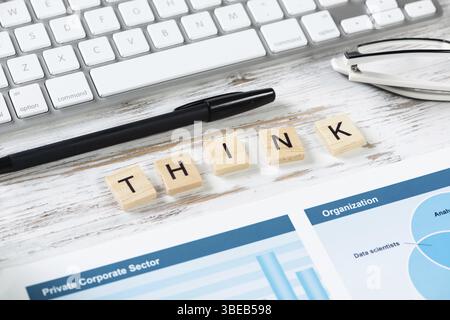 Denken Sie an ein Konzept mit Buchstaben auf Holzwürfeln. Stillleben des Büroarbeitsplatzes. Flacher Vintage-Holztisch mit Computertastatur, Stift und analytischem Repo Stockfoto