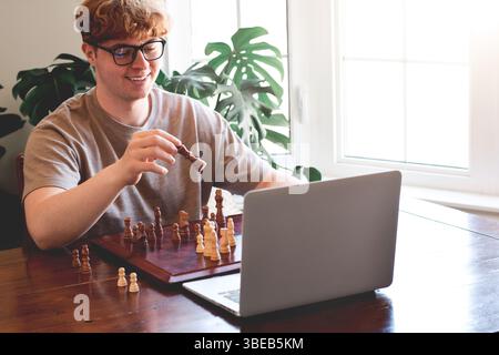 Junger Mann spielt Schach mit einem Freund durch Videochat Stockfoto