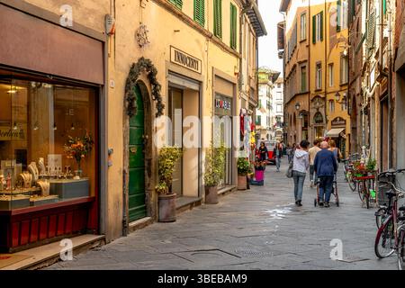Leute laufen entlang der Via Santa Croce, einer der Haupteinkaufsstraßen in Lucca, Italien Stockfoto